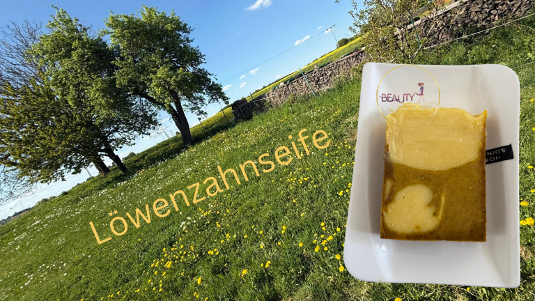 Löwenzahnseife und eine Wiese mit Bäumen sind zu sehen